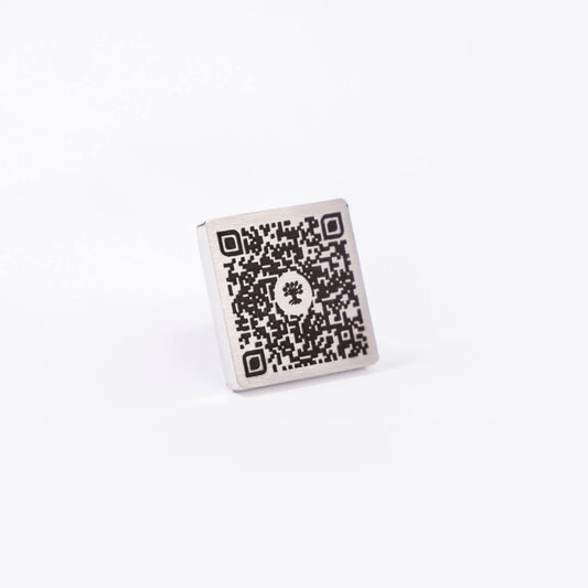 Plaque commémorative en acier inoxydable avec QR code gravé, vue en angle, permettant d’accéder à un profil hommage numérique sur la Plateforme Heritage.